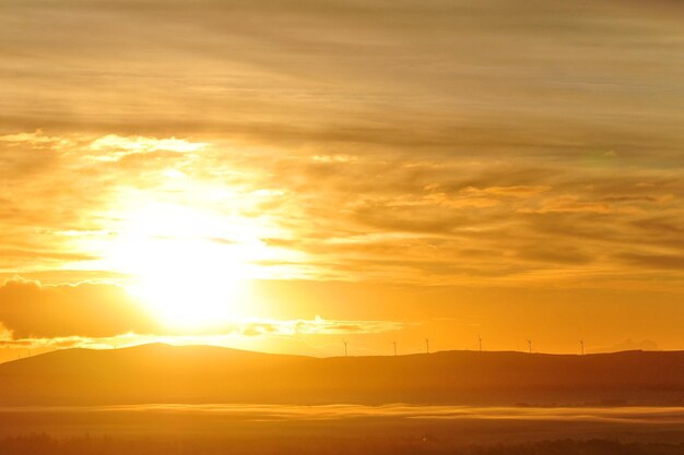 Low sun behind hilltop wind farm