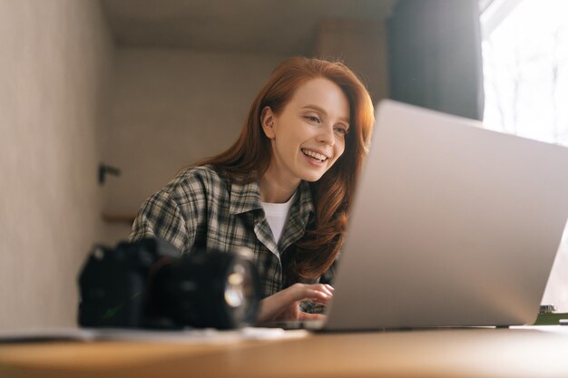 Lowangle-beeld van een vrouwelijke redacteur die in een thuisfotostudio werkt en een slechte opname op een laptop retoucheert