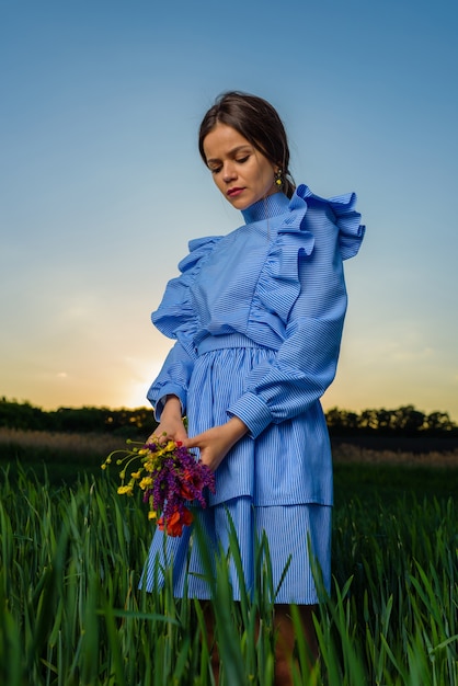 Foto angolo inferiore della giovane donna in abito a strisce blu e bianco