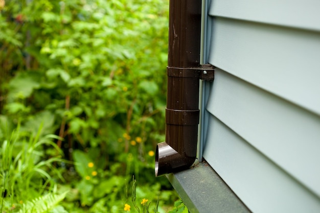 The lower part of a new plastic drain pipe on a country house or cottage shared by modern siding