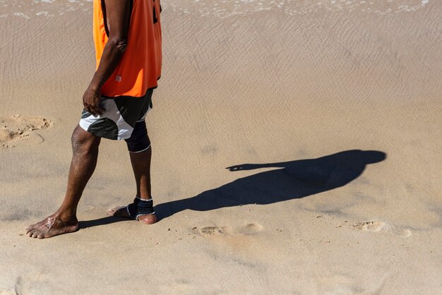 Lower part of a person and his shadow on the beach sand