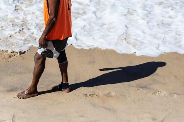 Lower part of a person and his shadow on the beach sand