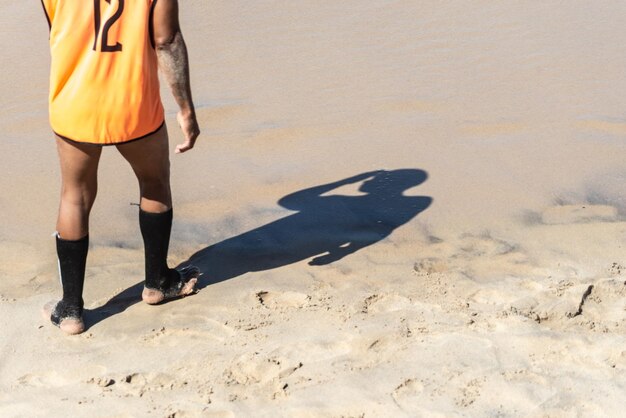 Lower part of a person and his shadow on the beach sand