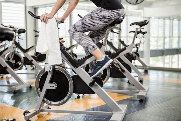 Lower section of fit woman on exercise bike at the gym