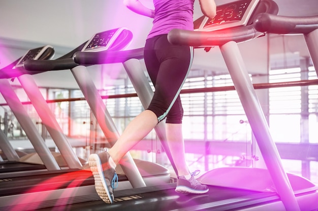 Lower section of fit woman on treadmill at gym