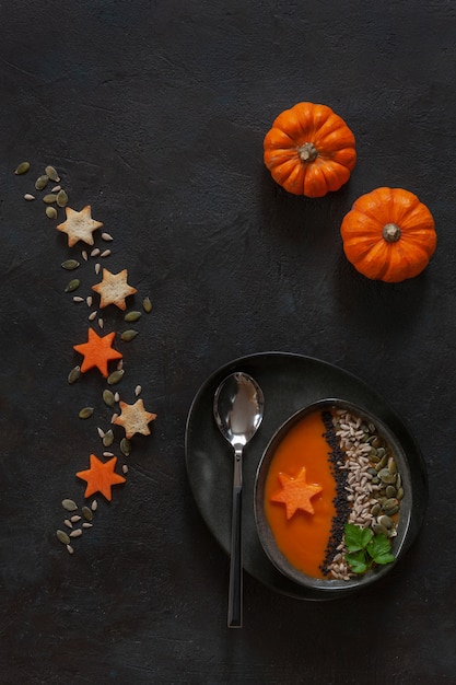 LTraditional pumpkin homemade cream-soup with seeds crackers and little pumpkins. 