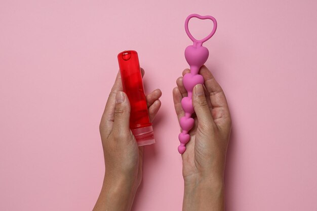 Photo lubricant with anal balls in hands on pink background