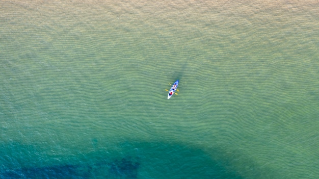 Lucht hoogste mening van het kayaking rond overzees met schaduw smaragdgroen blauw water en golfschuim