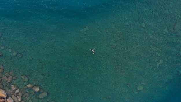 LUCHT: vrouw die op blauwe waterspiegel drijven, die in transparante Middellandse Zee zwemmen, top down mening, het concept van de de zomervakantie