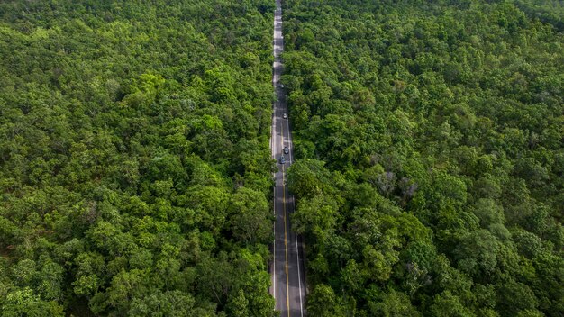 Luchtbeeld asfaltweg in het midden van de bossen met auto Asfaltweg door de berg en het groene bos