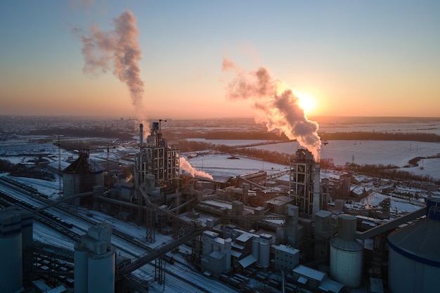 Foto luchtbeeld van de toren van de cementfabriek met een hoge betonnen fabrieksstructuur in het industriële productiegebied bij zonsondergang vervaardigings- en wereldwijd industrieconcept