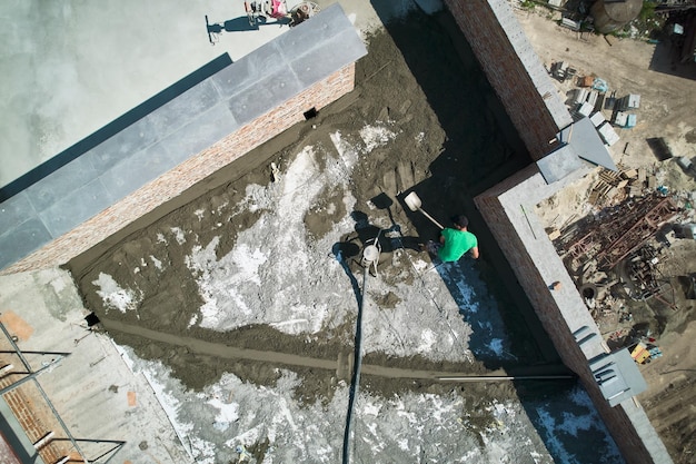 Luchtbeeld van een bouwvakker die een zandcementmengsel schept