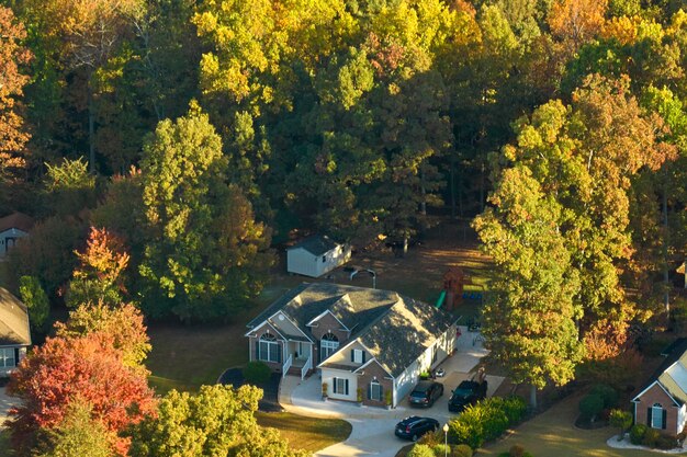 Foto luchtbeeld van een nieuw familiehuis tussen gele bomen in het voorstedelijk gebied van south carolina in het herfstseizoen onroerend goedontwikkeling in amerikaanse voorsteden