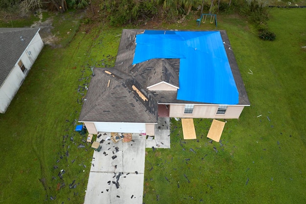 Foto luchtbeeld van het in de orkaan ian beschadigde dak van een huis dat met een blauwe beschermende tarp is bedekt tegen het lekken van regenwater tot de vervanging van de asfaltgordel