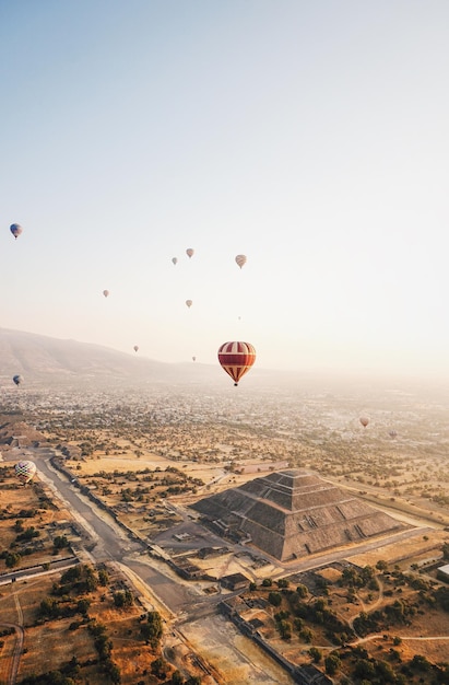 Foto luchtbeeld van luchtballonnen die over het landschap vliegen tegen de lucht.