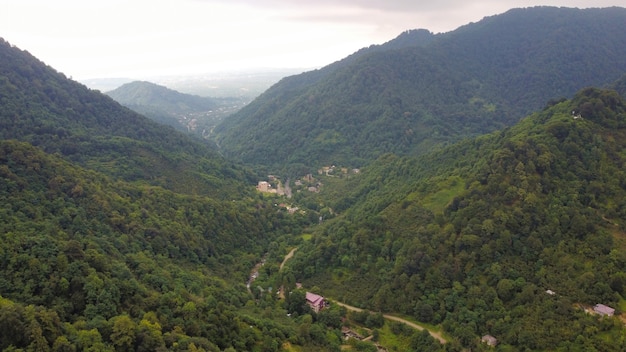 Luchtdrone-weergave van de natuur in Georgia Valley met smalle rivier- en dorpsheuvels