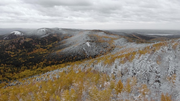 Luchtfoto 4k uitzicht op bergen bedekt door eerste sneeuw sneeuw op bergtoppen en prachtig groen dennenbos het winterseizoen komt eraan