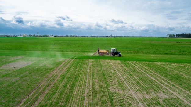 Luchtfoto Boer op tractor met sproeier maakt mest voor jonge groenten