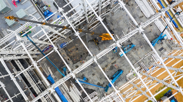 Luchtfoto bovenaanzicht bouwplaats met industriële machines bouwen voor nieuwe fabrieksgebouwen.