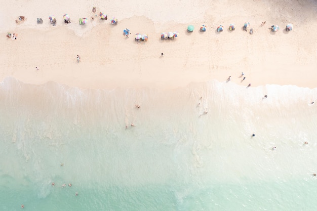 Luchtfoto bovenaanzicht toerist spelen in de zee op vakantie en paraplu op het strand zomervakantie concept