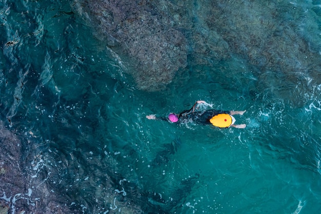 Luchtfoto bovenaanzicht van drone van een zwemmer in open water met wetsuit en boei