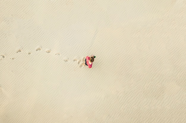 Luchtfoto bovenaanzicht van jonge eenzame man lopen in de woestijn op het zand textuur. verloren concept