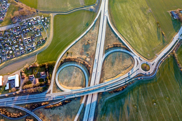 Luchtfoto bovenaanzicht van moderne snelweg kruispunt, huis daken op lente groen veld. drone fotografie.