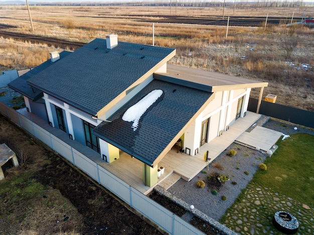 Foto luchtfoto bovenaanzicht van nieuwe woonhuis cottage en terras met grind dak op omheinde grote tuin op zonnige winterdag.