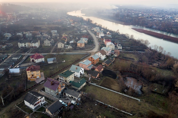 Luchtfoto bovenaanzicht van rivier stroomt door de stad. Landelijk landschap van woonhuizen, wegen en bomen op lente- of herfstdag. Drone fotografie.