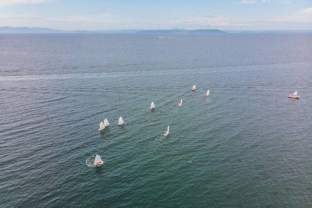 Luchtfoto drone foto van jonge tieners op kleine zeilboten die strijden in de regatta op de Middellandse Zee smaragdgroen.