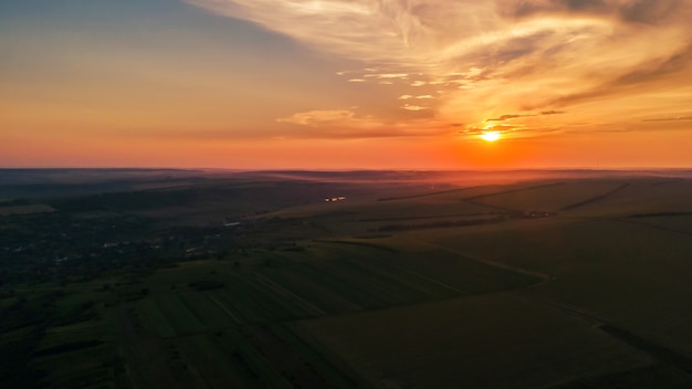 Luchtfoto drone panorama uitzicht op de natuur in Moldavië bij zonsondergang. Dorp, uitgestrekte velden, heuvels