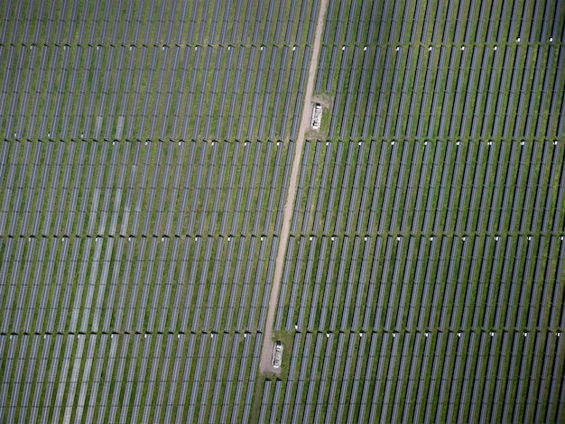 Luchtfoto drone uitzicht op zonne-energiecentrale in groene weide op zonnige dag.