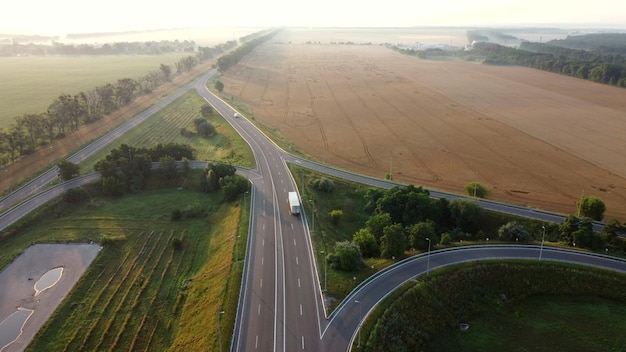 Luchtfoto drone-vlucht over autoweg tussen landbouwtarwevelden