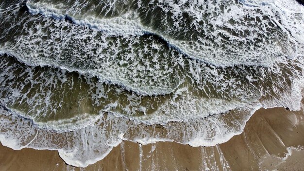 Foto luchtfoto drone-vlucht over zeegolven die op zandige kust rollen