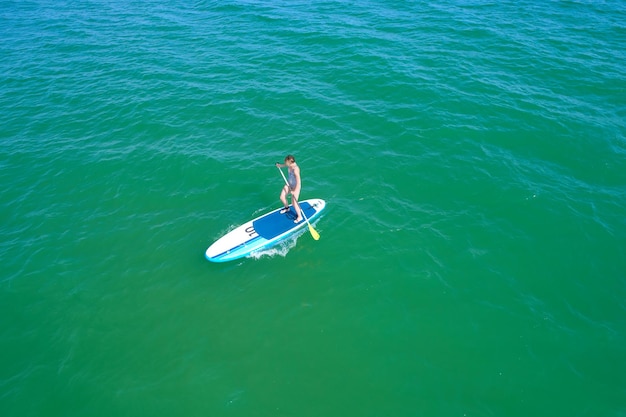 Luchtfoto drone vogelperspectief van jonge vrouw die sup board uitoefent in turquoise tropische heldere wateren