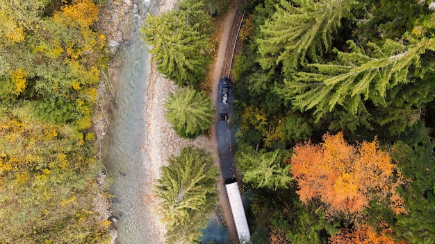 Luchtfoto drone-weergave van de bewegende stoomtrein Mocanita in een vallei langs een rivier bedekt met heuvels