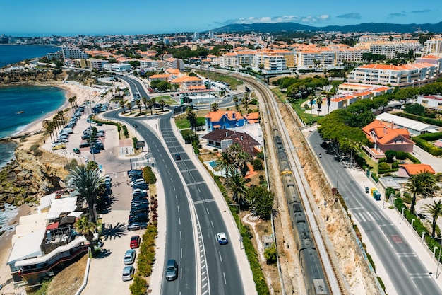 Luchtfoto drone-weergave van trein passeren in de buurt van de Marginal Avenue en kustlijn met Parade district in Groot-Lissabon Portugal