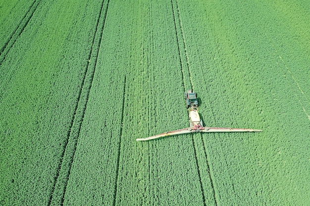 Luchtfoto Landbouwmachines spuiten chemicaliën op het grote groene veld, landbouw lente achtergrond.