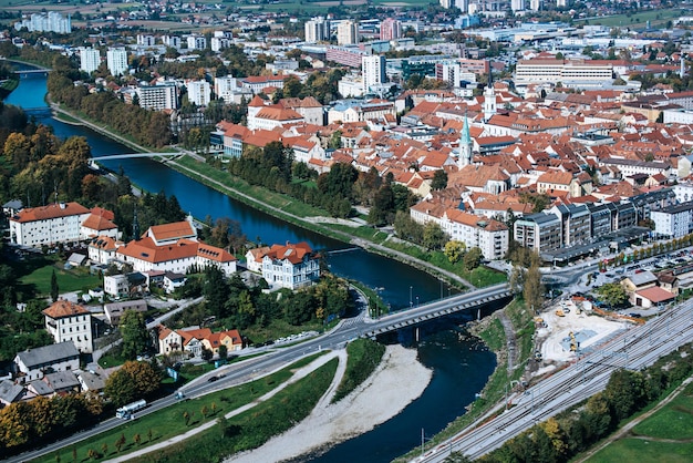 Luchtfoto naar de stad Celje in Slovenië. Rode daken, rivier en de brug. Buiten reizen achtergrond.