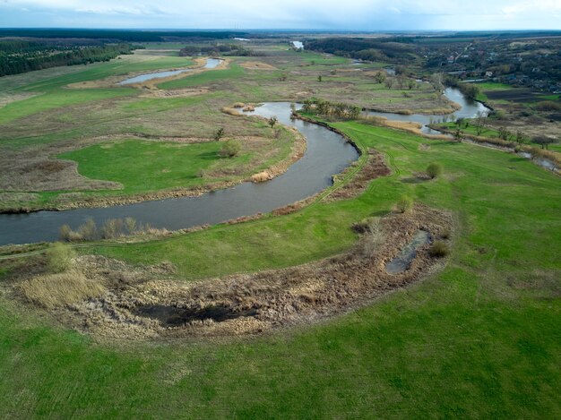 Luchtfoto over het riviertje dat op de groene weide ligt