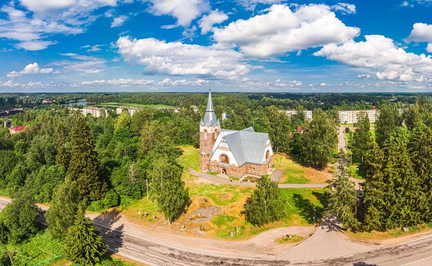 Foto luchtfoto panoramisch uitzicht op de oude lutherse kerk kirk ryaysyalya ontworpen door architect joseph stenback in stijl van de finse romantiek art nouveau in zonnige zomerdag melnikovo leningrad regio rusland