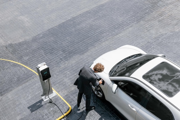 Luchtfoto progressieve zakenmensen met EV-auto en laadstation