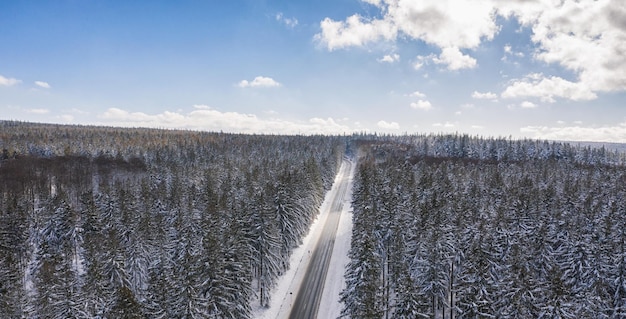 Luchtfoto van auto's die over de weg rijden door het bos bedekt met sneeuw in de winter en bewolkte hemel, inclusief kopieerruimte