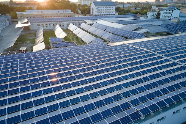 Luchtfoto van blauwe fotovoltaïsche zonnepanelen gemonteerd op het dak van een industrieel gebouw voor het produceren van groene ecologische elektriciteit in de avond Productie van duurzaam energieconcept