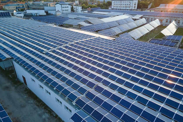 Luchtfoto van blauwe fotovoltaïsche zonnepanelen gemonteerd op het dak van een industrieel gebouw voor het produceren van groene ecologische elektriciteit Productie van duurzaam energieconcept