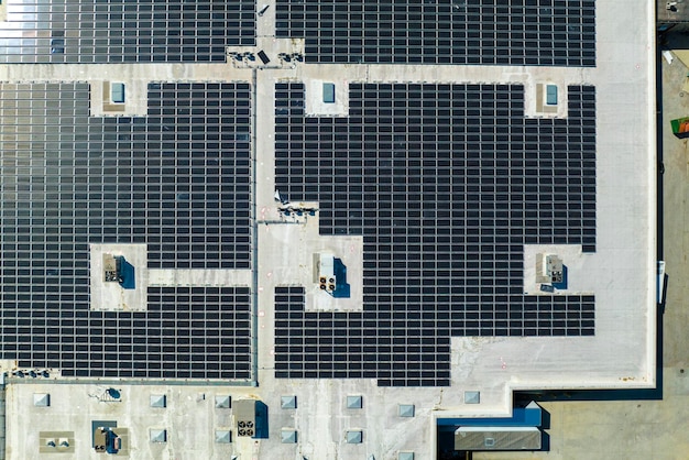 Luchtfoto van blauwe fotovoltaïsche zonnepanelen gemonteerd op het dak van een industrieel gebouw voor het produceren van schone ecologische elektriciteit Productie van een concept van hernieuwbare energie