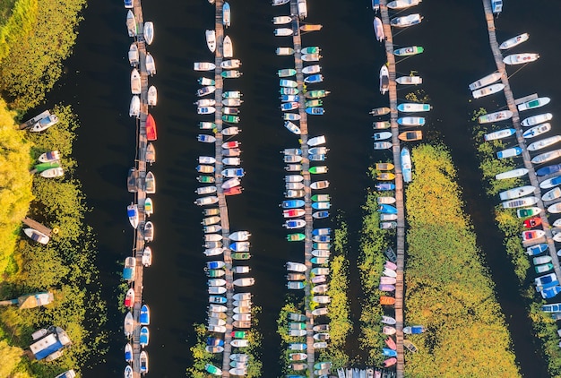 Luchtfoto van boten en luxe jachten in dok bij zonsondergang in de zomer Kleurrijk landschap met zeilboten en motorboten in rivierbaai steigerwater Bovenaanzicht vanaf gedreun van haven Vervoer