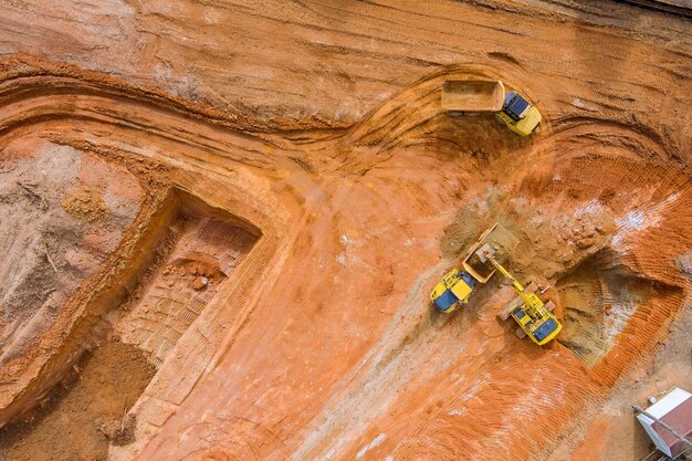 Luchtfoto van boven van de graafmachine die de kantelwagen op het bouwterrein laadt