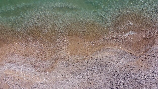 Luchtfoto van bovenaf op azuurblauwe zee en roze kiezelstrand kleine golven op kristalhelder water