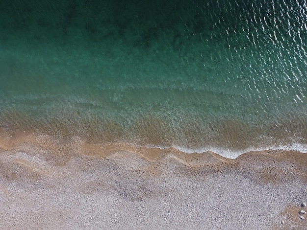 Luchtfoto van bovenaf op azuurblauwe zee en roze kiezelstrand kleine golven op kristalhelder water